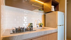 Eine moderne Küche mit weißen, rechteckigen Fliesen, einer Edelstahl-Spüle, einem eingebauten Gasherd und einem weißen Kühlschrank.