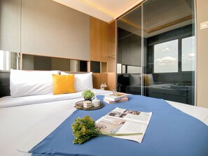 Een moderne hotelkamer met een groot bed, een nachtkastje met een plant, een dienblad met decoratieve items en een tijdschrift.