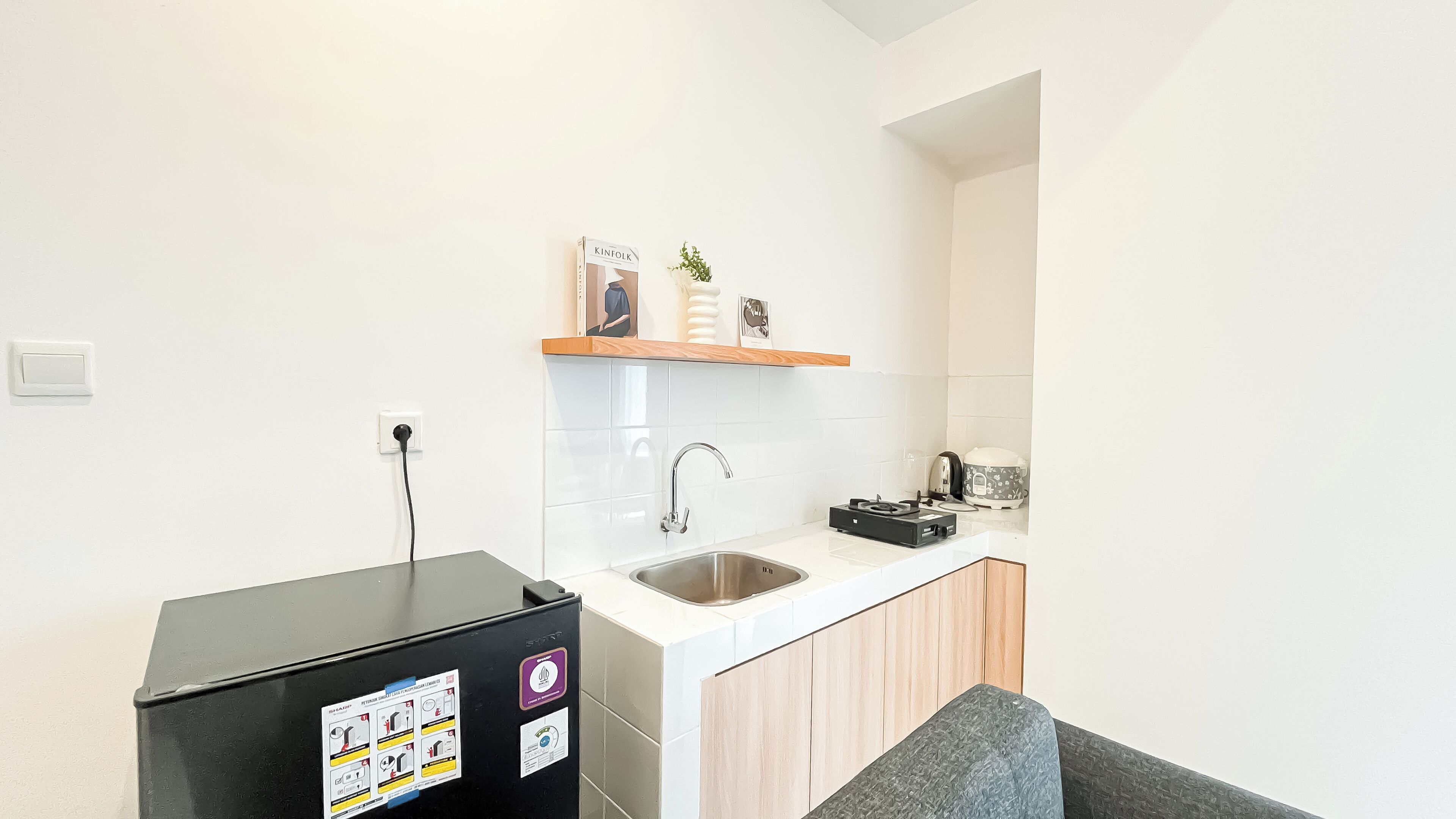 A compact kitchen with a sink, a countertop, and a small refrigerator.