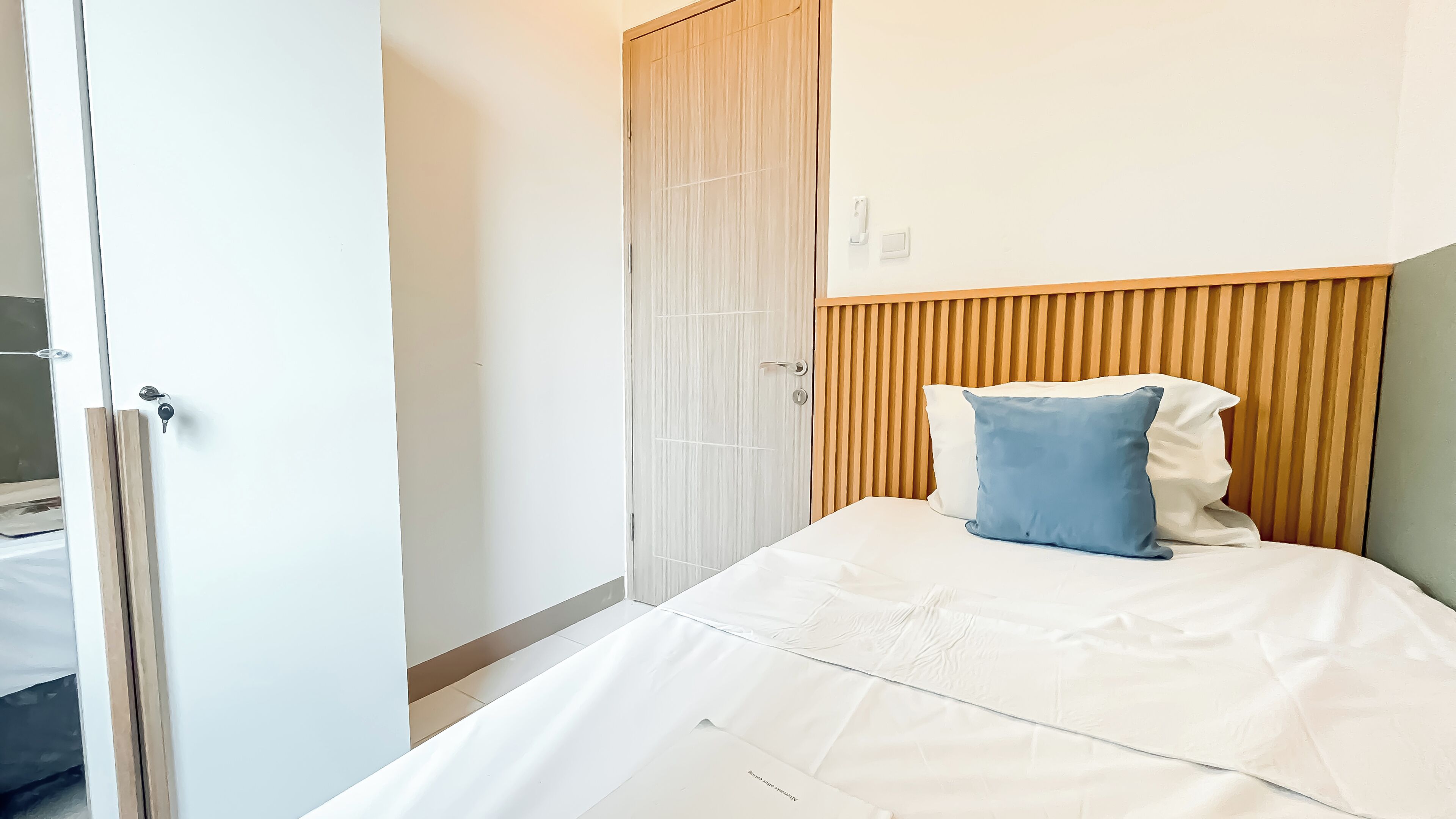 A bedroom with a bed, a wooden headboard, a white door, and a wooden wardrobe.
