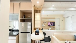 A modern kitchen with a refrigerator, sink, and a dining area with a table and chairs. - Warm And Comfy 2Br At Green Bay Pluit Apartment (Jakarta)