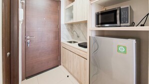 A compact kitchen with a microwave, a refrigerator, and a sink. - Delightfully Cozy Studio Apartment Pacific Garden - Campus Town @Alam Sutera (Tangerang)