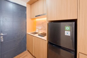 A modern kitchen with a stainless steel refrigerator, wooden cabinets, and a marble countertop. - Comfortable And Relaxing Living In Studio At Apartment Collins Boulevard (Tangerang)