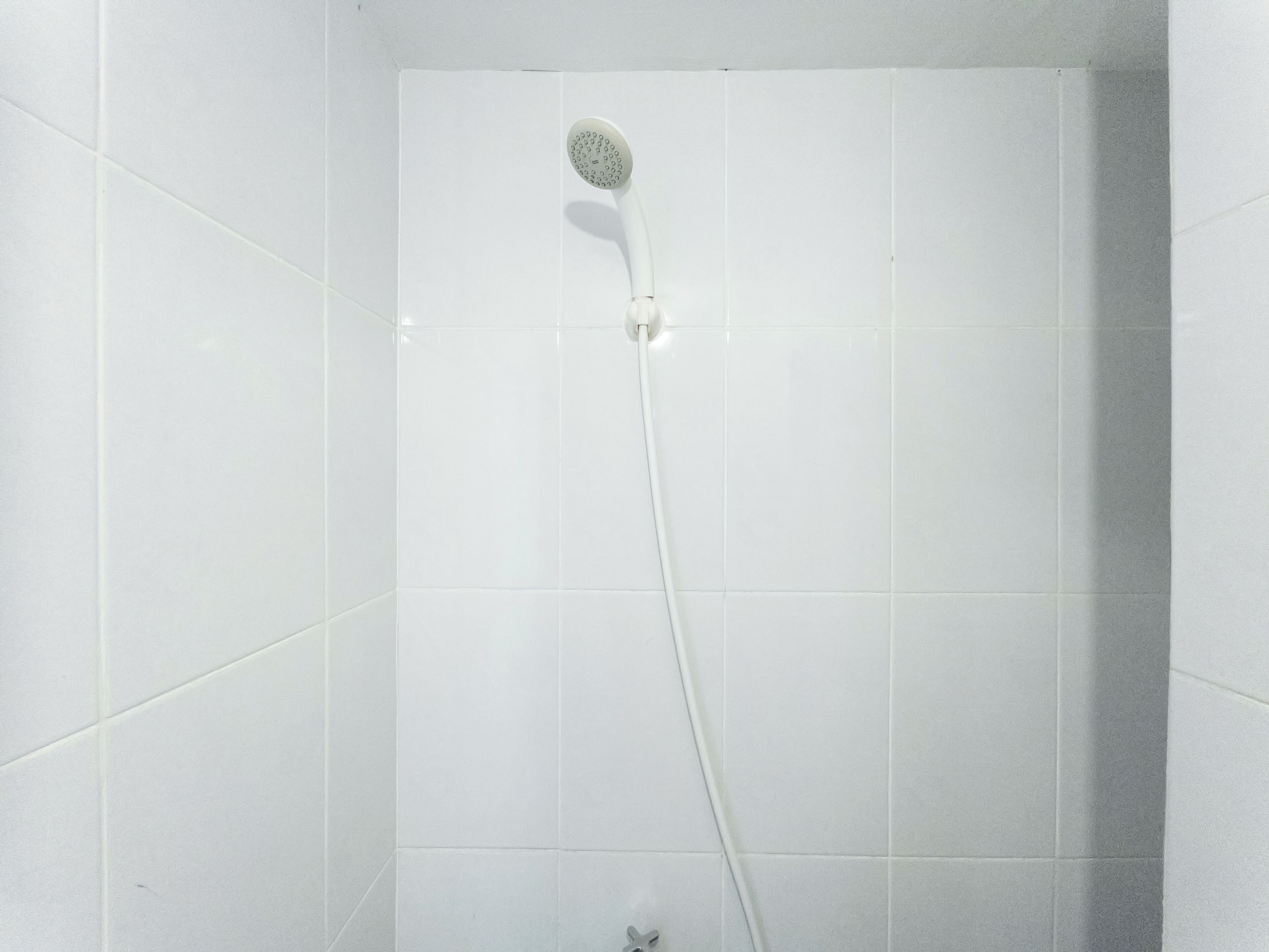 Eine Dusche mit Duschbrause in einem gefliesten Badezimmer.