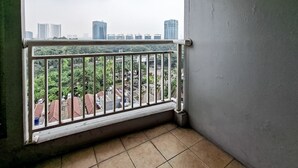 Ein Balkon mit Metallgeländer und Blick auf eine Stadtlandschaft mit Gebäuden und Grünflächen.