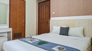 Ein Hotelzimmer mit Bett, Holzschrank, Schreibtisch und Fenster.