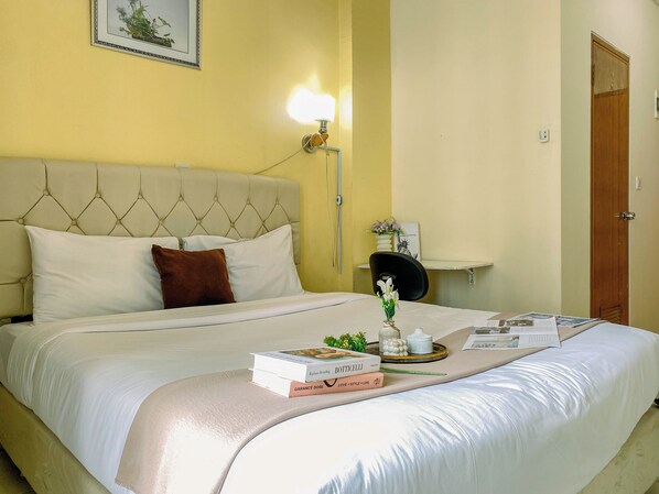 A neatly made bed with a headboard, a bedside table with a lamp, and a framed picture on the wall. - Neat And Compact Studio At Dave Apartment (Depok)