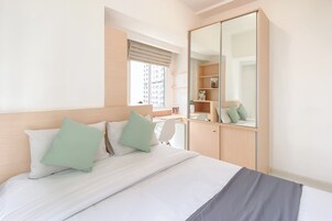 A neatly arranged bedroom with a bed, a wardrobe, and a desk.