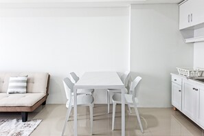 Et moderne, minimalistisk rum med en hvid sofa, et hvidt spisebord med stole og hvide skabe.