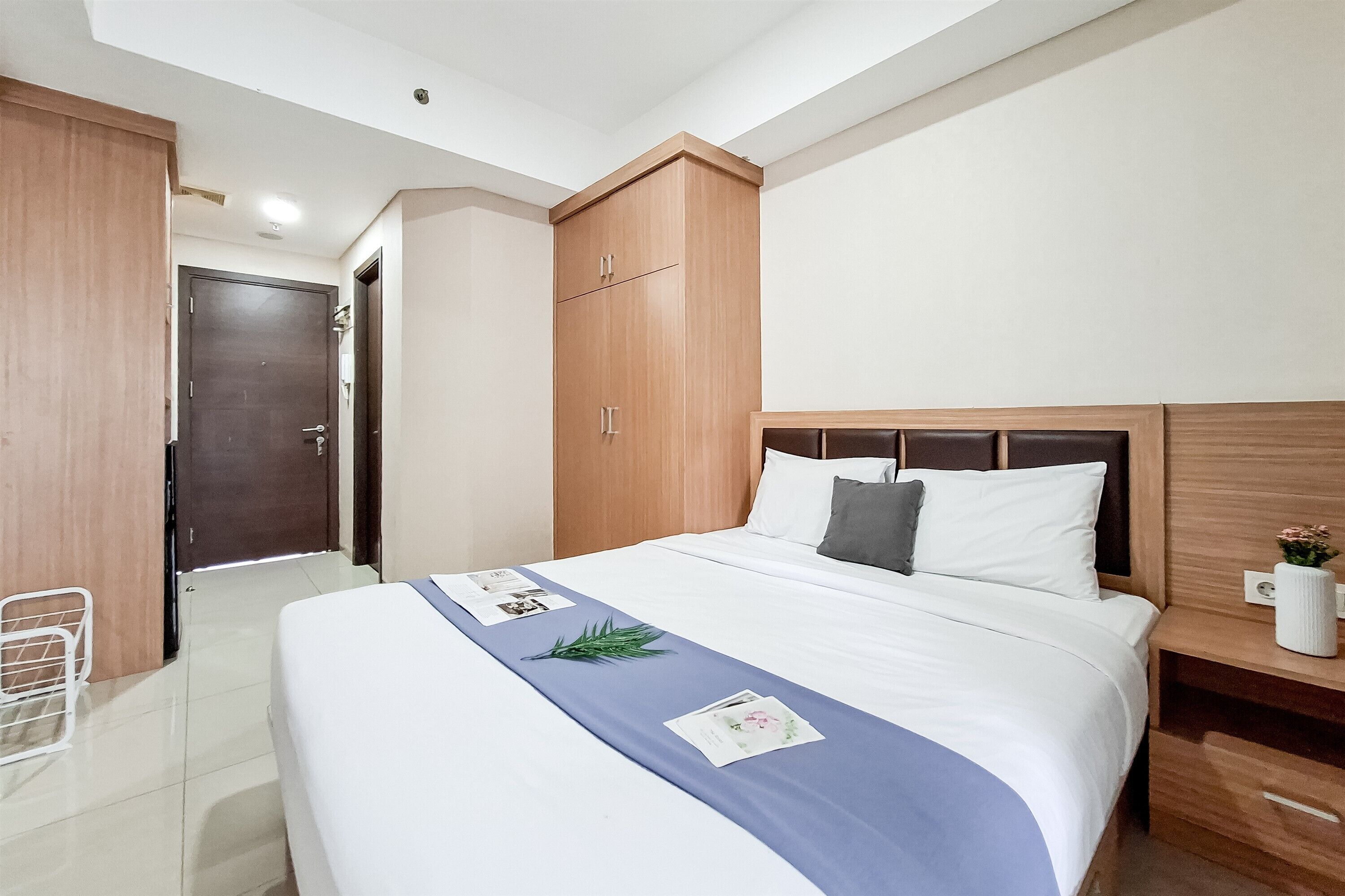 Een hotelkamer met een bed, een houten garderobe en een nachtkastje.