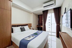 Ein Hotelzimmer mit Bett, Schreibtisch, Klimaanlage und einem Vorhangfenster.