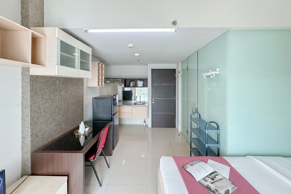 Een moderne hotelkamer met een bed, bureau en kitchenette.