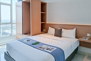 Ein modernes Hotelzimmer mit einem großen Bett, einem Holzschrank und Blick auf die Stadt durch ein großes Fenster.