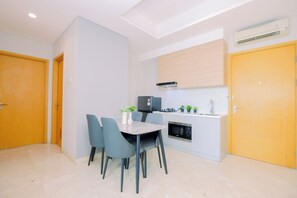 A modern kitchen with a dining area, featuring a built-in oven, microwave, and a small island with plants. - Spacious Grey 2Br At Capitol Suites Apartment (Jakarta)