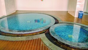Un espace piscine comprenant deux piscines circulaires et un sol carrelé.