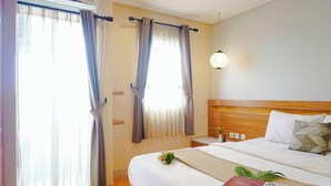 Une chambre d’hôtel avec un lit, des rideaux, une table de chevet, une lampe et une fenêtre.