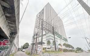 A tall building with scaffolding, surrounded by power lines and a street with cars. - Adequate And Comfortable Studio At Bale Hinggil Apartment (Surabaya)