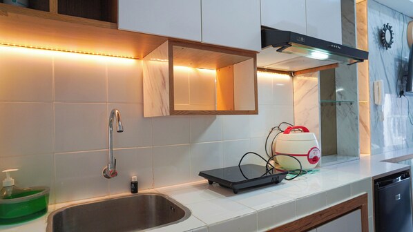 A modern kitchen with a stainless steel sink, a built-in oven, and a microwave on the countertop. - Classic Modern Studio At Apartment Tokyo Riverside Pik 2 (Teluknaga)