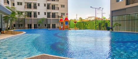 Una piscina con cubierta de madera, rodeada de edificios de varios pisos con balcones.