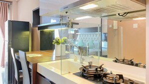 A modern kitchen with a glass partition, stainless steel appliances, and a view of the living area. - Lovely And Cozy Studio Room At Apartment Signature Park Grande (Jakarta)