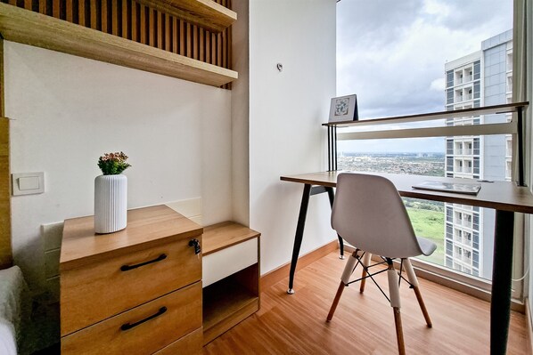 Ein modernes Zimmer mit einem Holztisch, einem Stuhl und Blick auf eine Stadtlandschaft durch große Fenster.