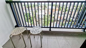 A balcony with two perforated metal chairs and a view of a cityscape. - Magnificent 1Br At Apartment Anwa Residence (South Tangerang)