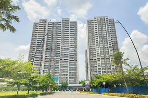 Un moderno edificio de rascacielos con varios pisos, rodeado de vegetación y un cielo despejado.