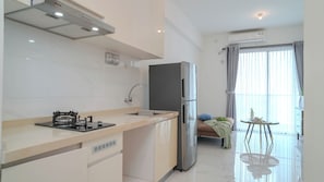 Una cocina moderna con estufa a gas, pileta y refrigerador de acero inoxidable. Cuenta con un pequeño comedor con mesa y sillas.