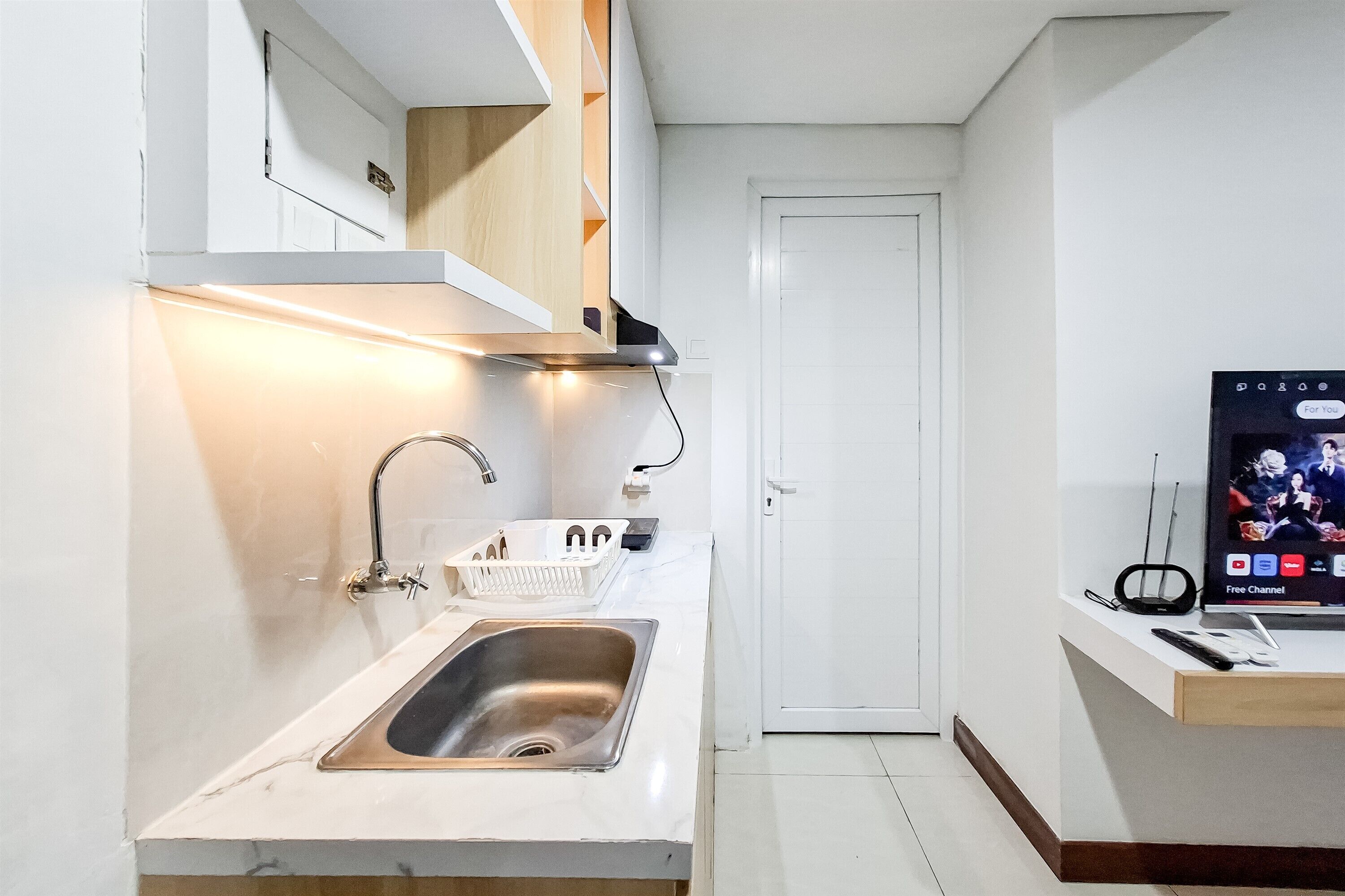 A modern kitchen with a stainless steel sink, white marble countertop, and built-in wooden shelves.