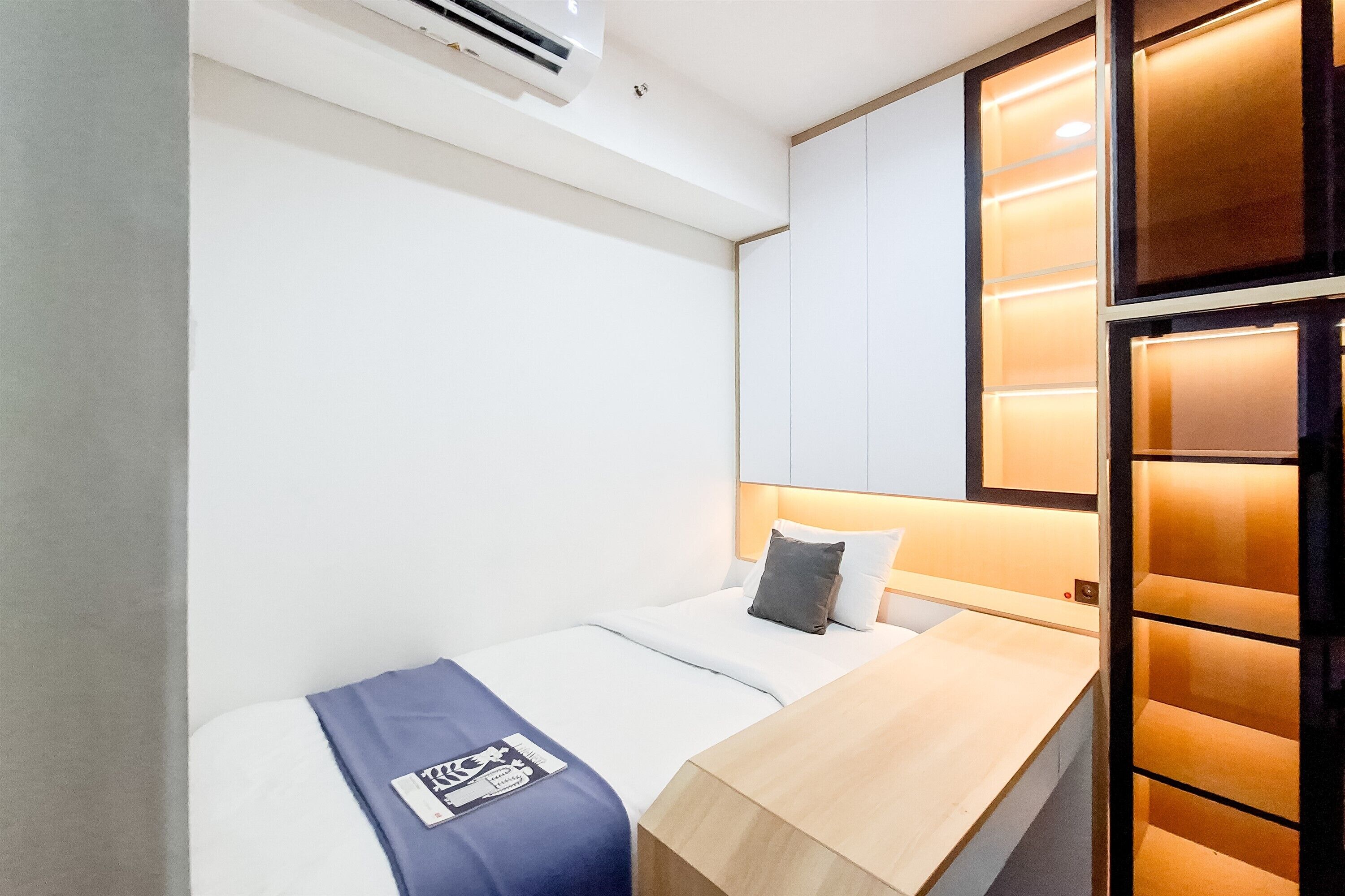 Una habitación de hotel moderna con una cama individual, un escritorio de madera y un ventanal con vistas.