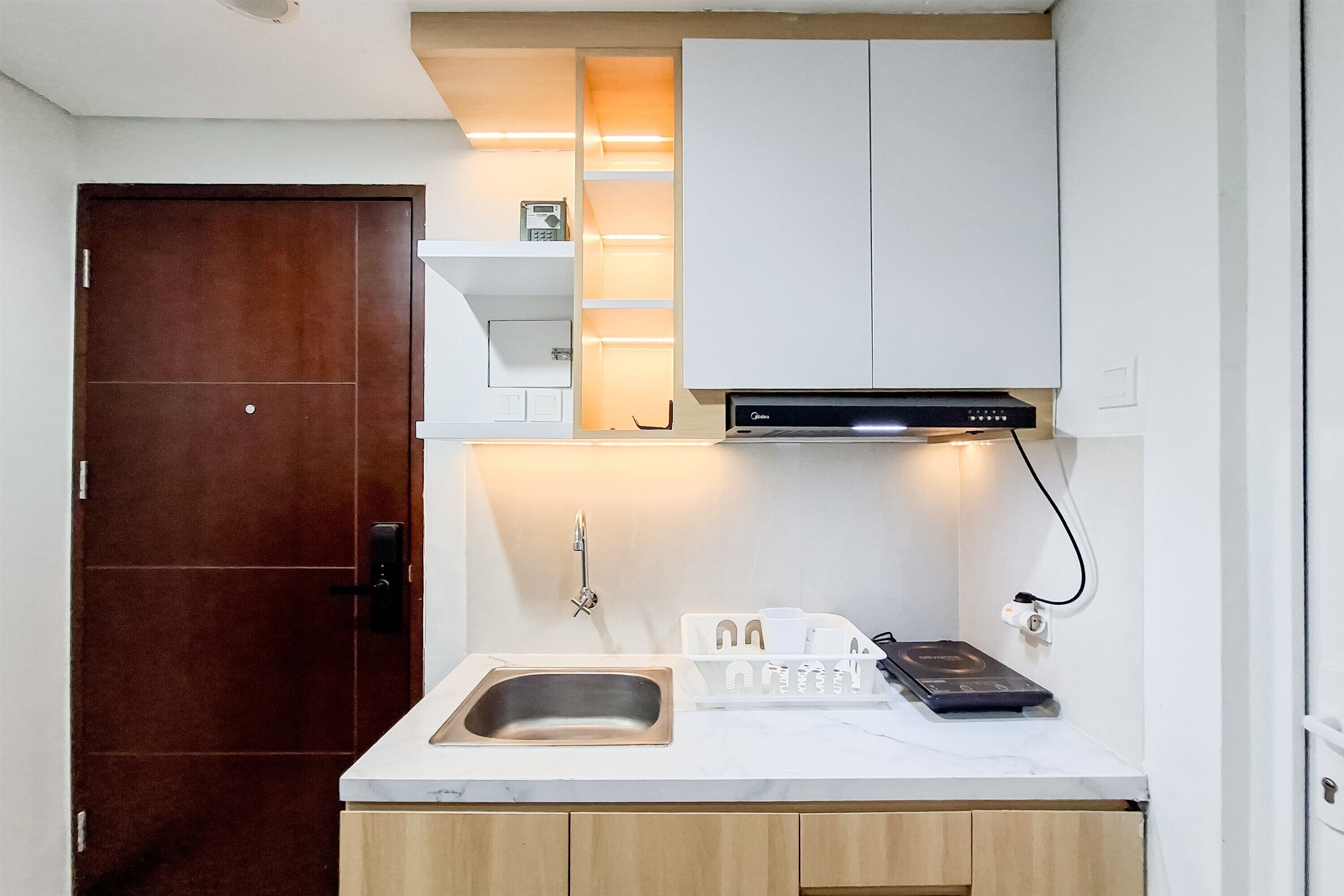 A compact kitchen with a stainless steel sink, a built-in oven, and white cabinetry.
