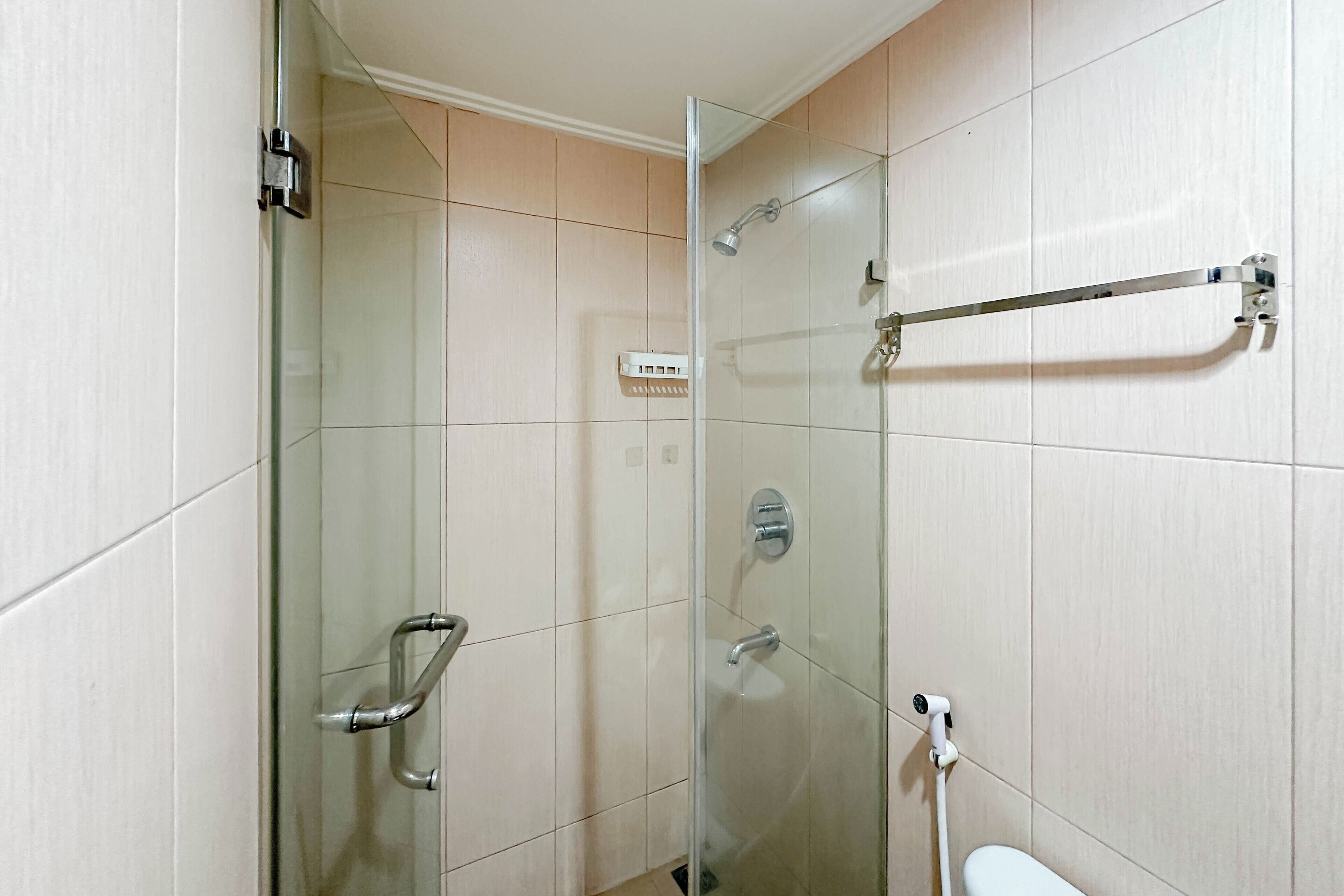 Uma casa de banho moderna com cabine de duche em vidro, lavatório branco e porta-toalhas.
