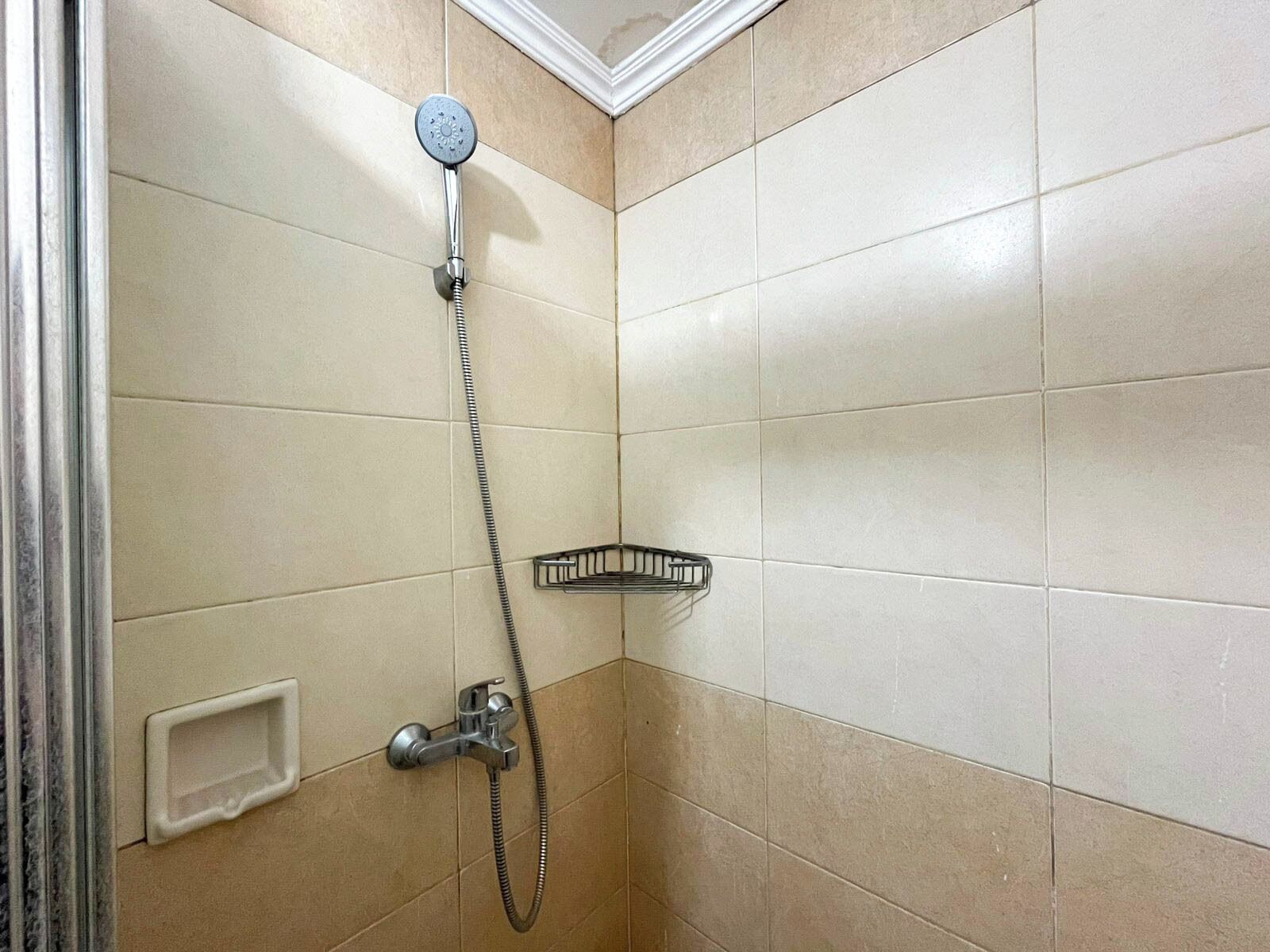 Eine Eckdusche mit Handbrause, ein Handtucharmatur und ein Eckwaschbecken mit Seifenschale.