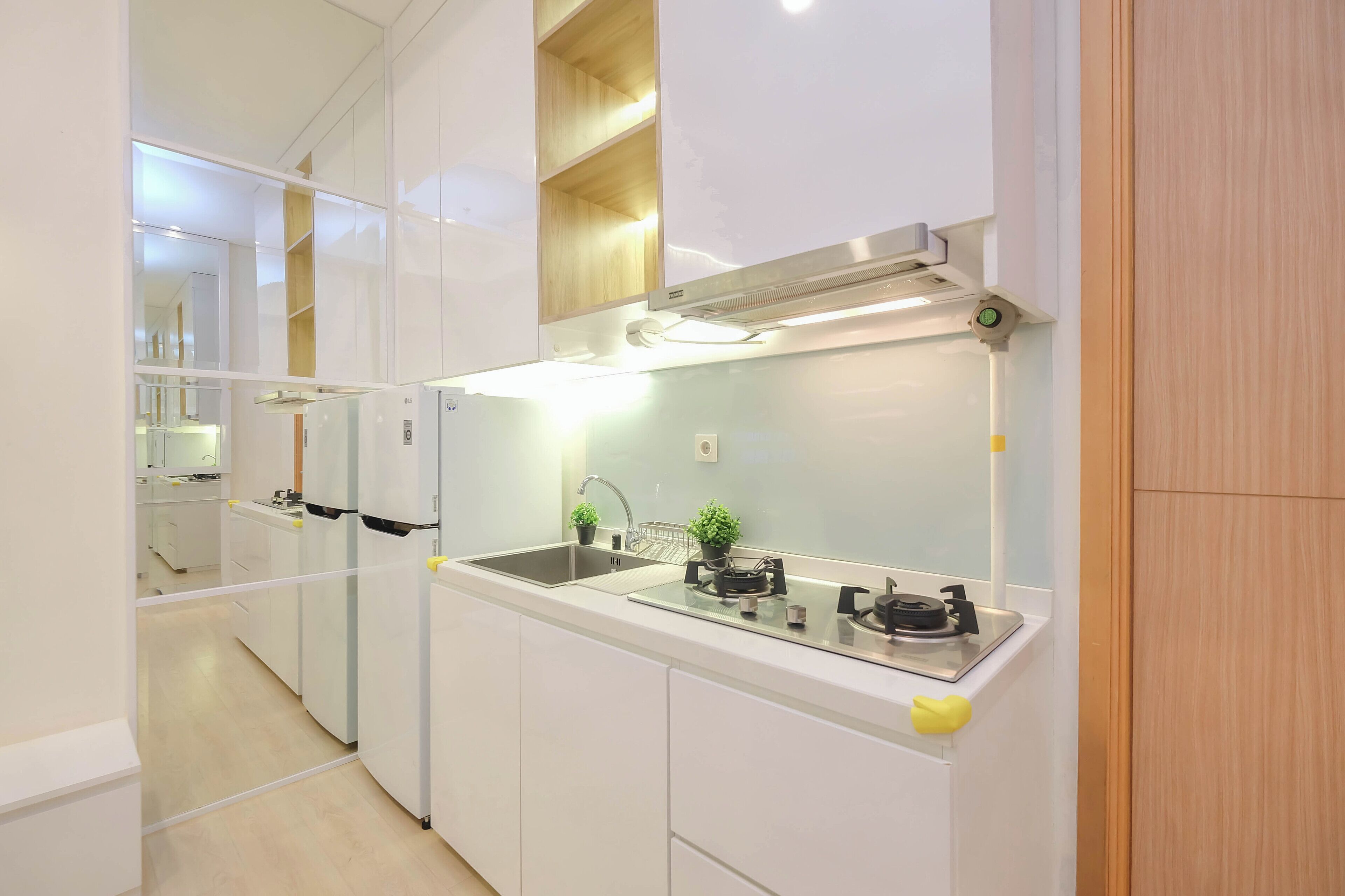 Una cucina moderna con mobili bianchi, un lavello in acciaio inossidabile, un piano cottura a gas e un forno integrato.