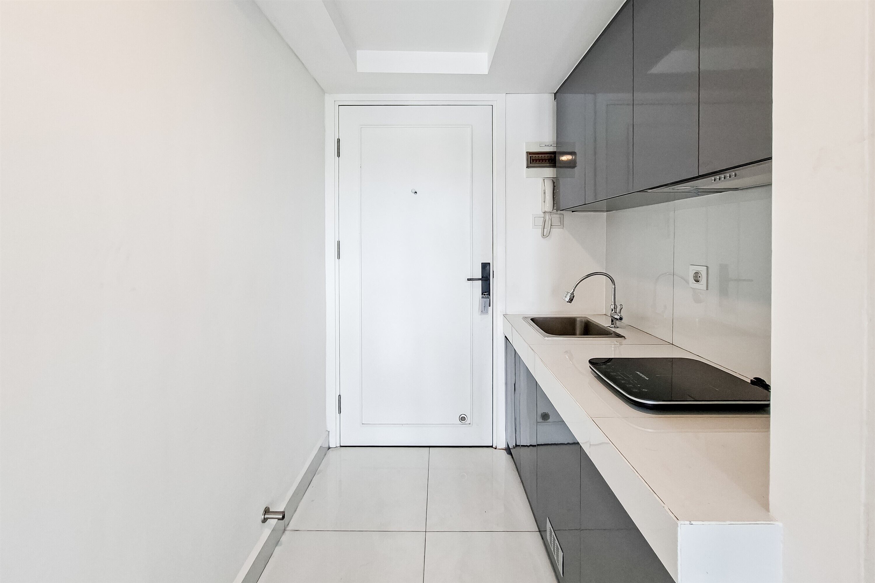 Una cocina moderna con una puerta blanca, un fregadero y una encimera negra.