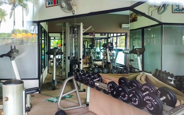 Une salle de sport équipée de matériel d’exercice, notamment des haltères, un tapis de course et des appareils de musculation.