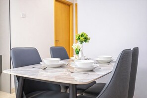 Et spisebord med fire stole, hvide tallerkener og en vase med blomster.