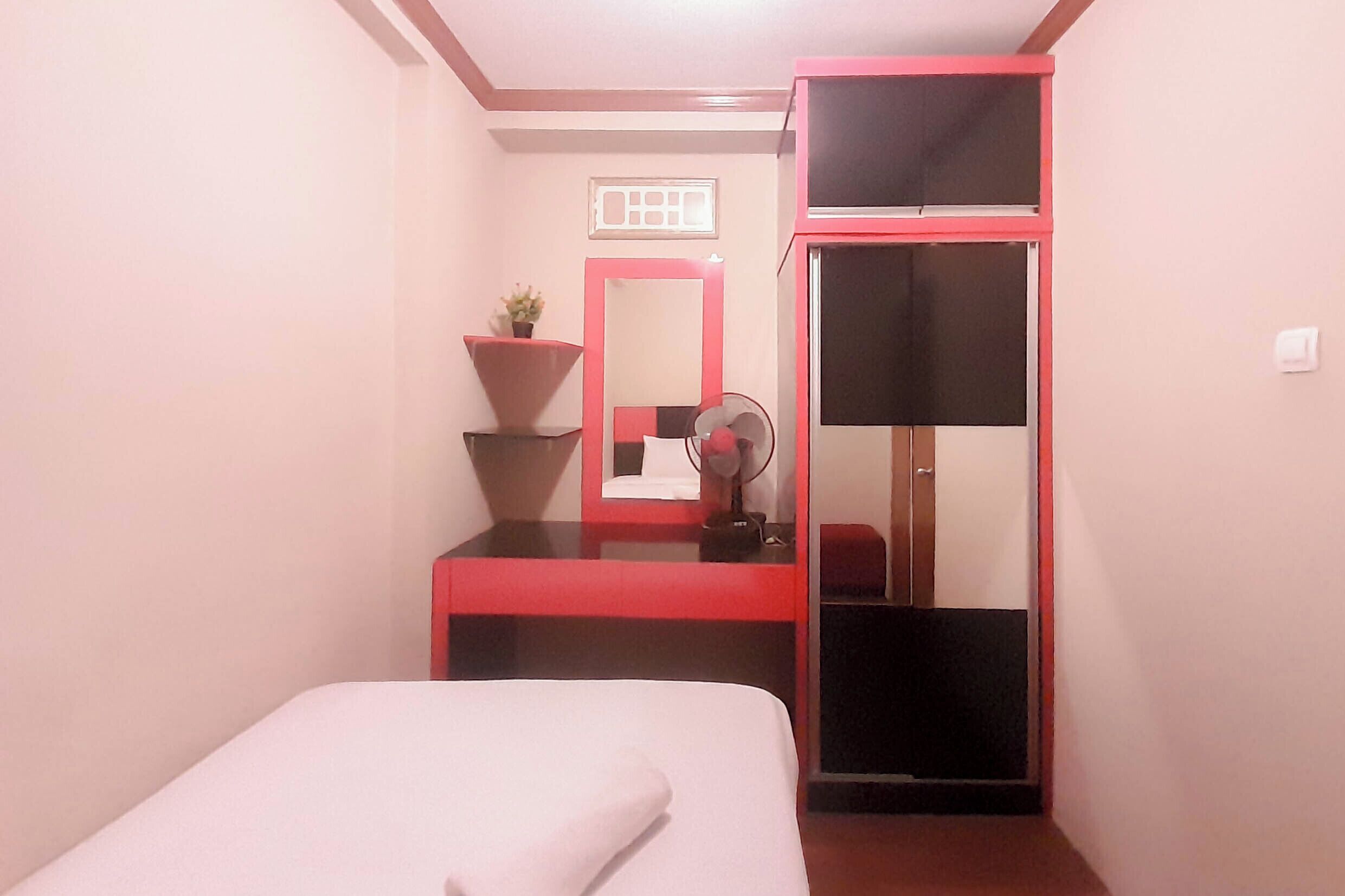 A bedroom with a bed, a desk with a mirror, and a wardrobe.