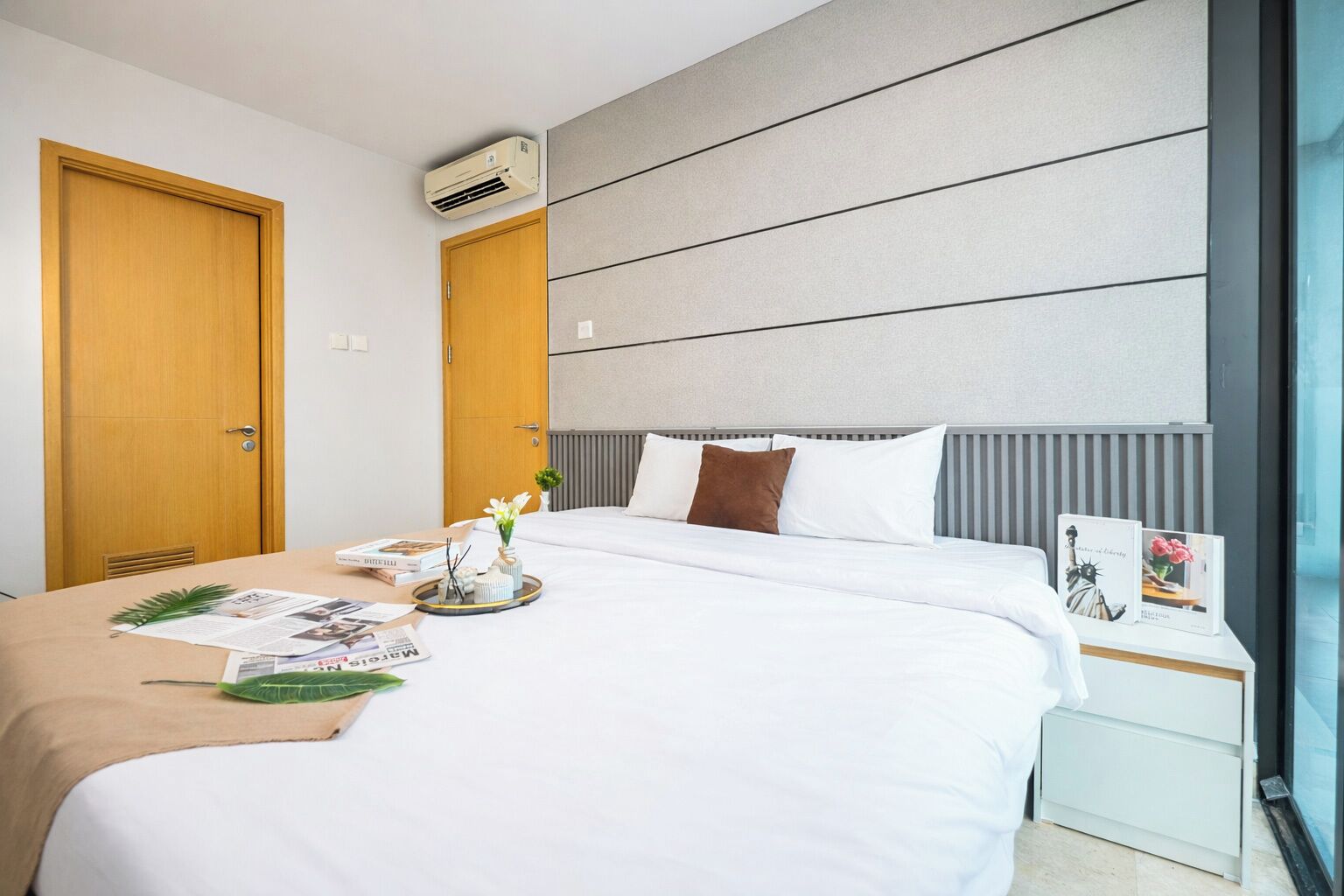 Een moderne hotelkamer met een groot bed, een nachtkastje met een lamp en een raam met uitzicht.