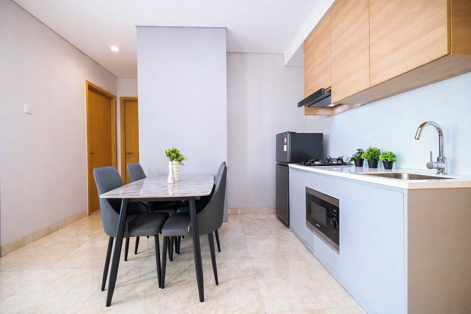 A compact kitchen with a built-in oven and a gas stove, a dining table with chairs, and a small countertop with a sink.