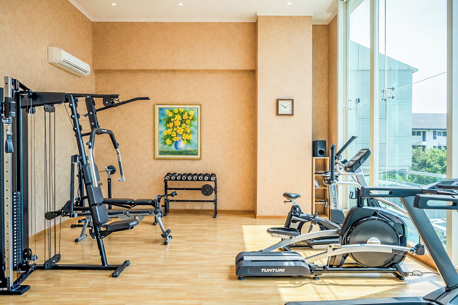 Uma academia com equipamentos de ginástica, um banco e um quadro de flores.