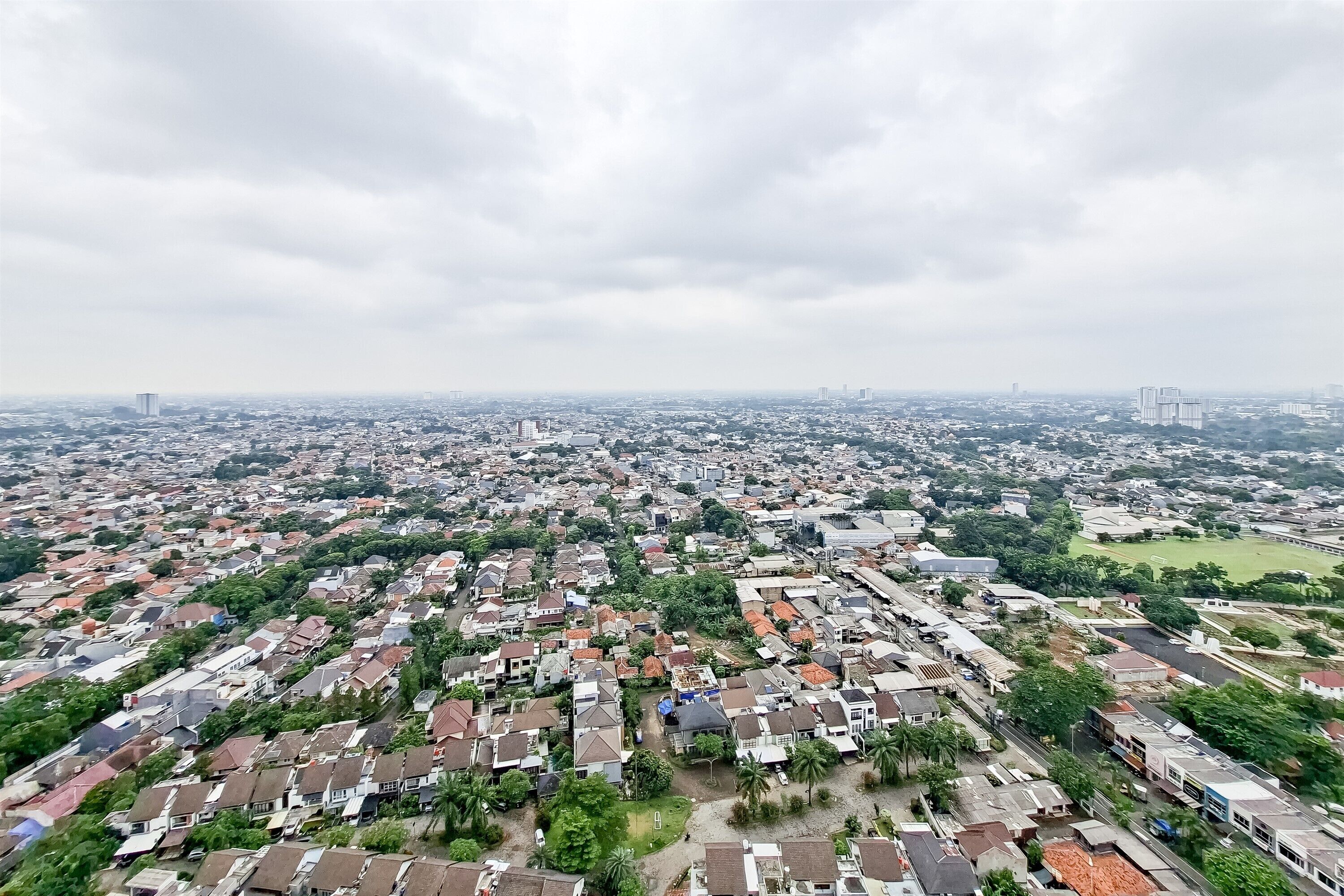 An aerial view of a densely populated urban area with numerous residential buildings, roads, and green spaces.