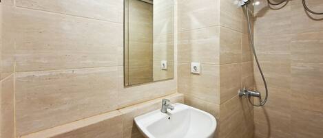 Un baño con lavamanos blanco, espejo y ducha.