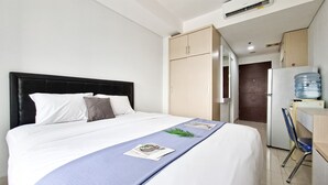 Ein Hotelzimmer mit einem Bett, einem Kleiderschrank, einem Schreibtisch mit Stuhl und einem Wasserspender.