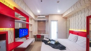 A modern hotel room with a bed, a TV, a desk, and a bathroom. - Simply Studio Apartment Near Unpar At Parahyangan Residence (Bandung)