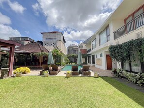 Une cour avec une piscine, des chaises longues et une pergola.