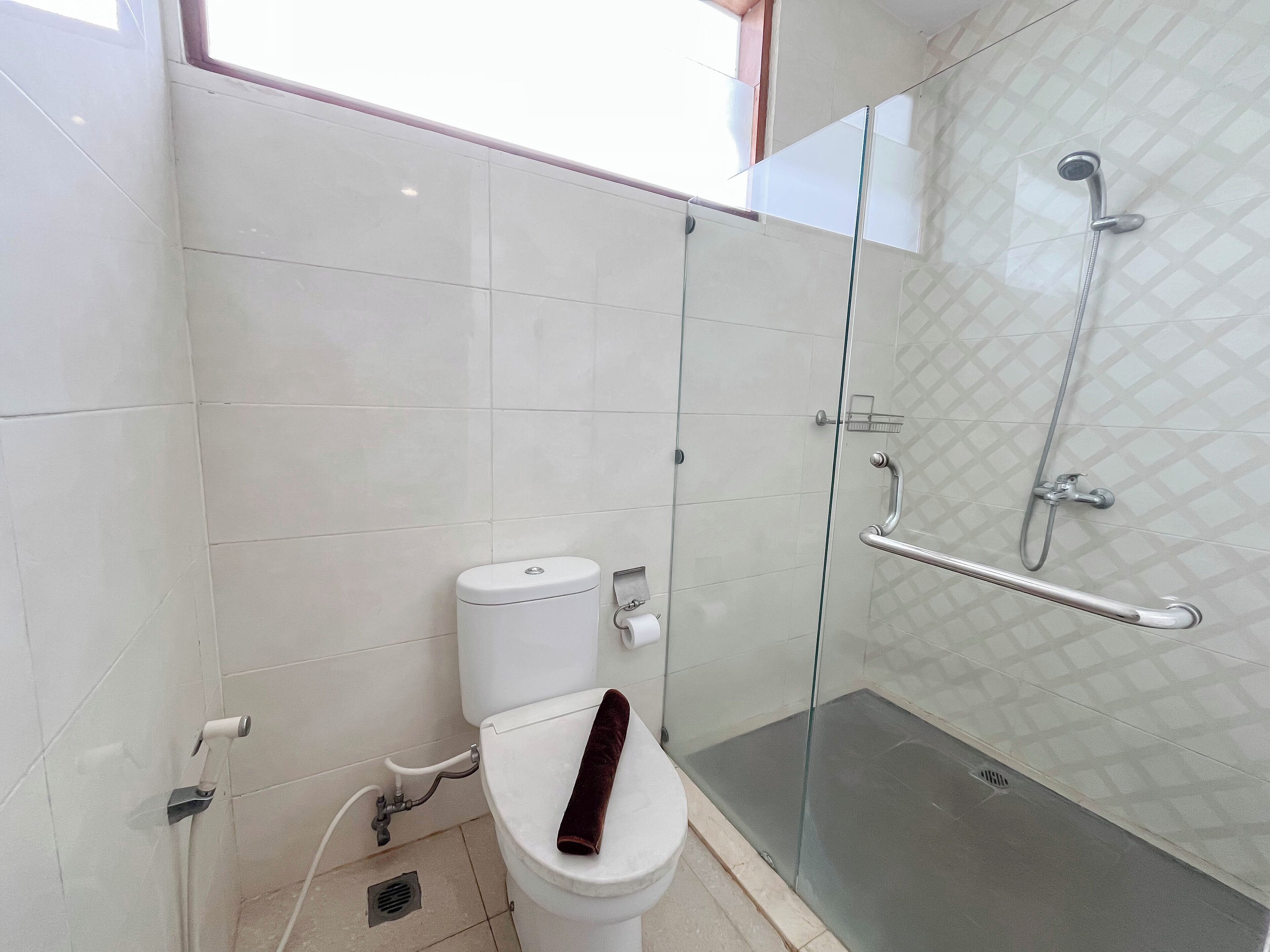 Une salle de bain moderne équipée de toilettes, d’une douche à parois de verre et d’une barre d’appui.