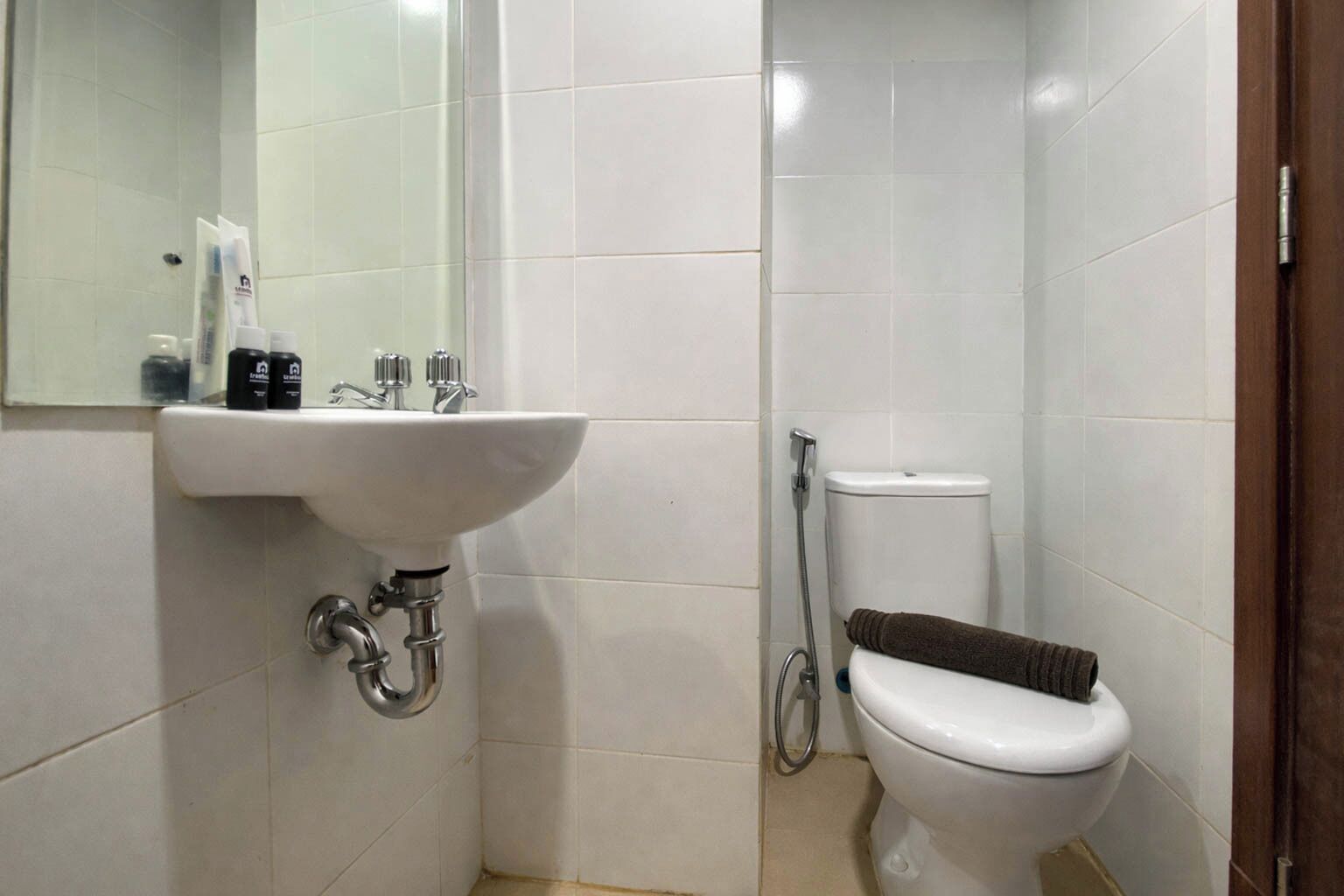 A small bathroom with a white sink, a toilet, and a mirror.