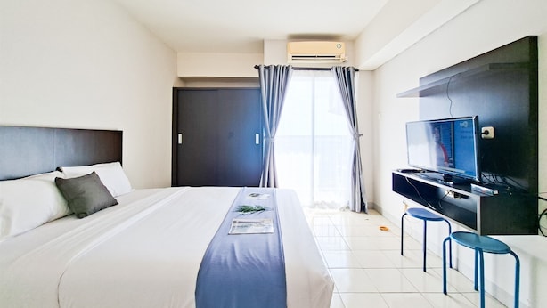 Una habitación de hotel con una cama, un televisor de pantalla plana y un escritorio con dos sillas.