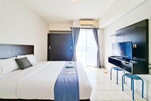 Una habitación de hotel con una cama, un televisor de pantalla plana y un escritorio con dos sillas.